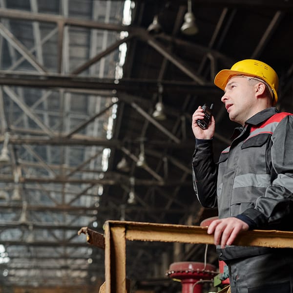 Foreman in workwear speaking in the radio set and controlling the work in the factory